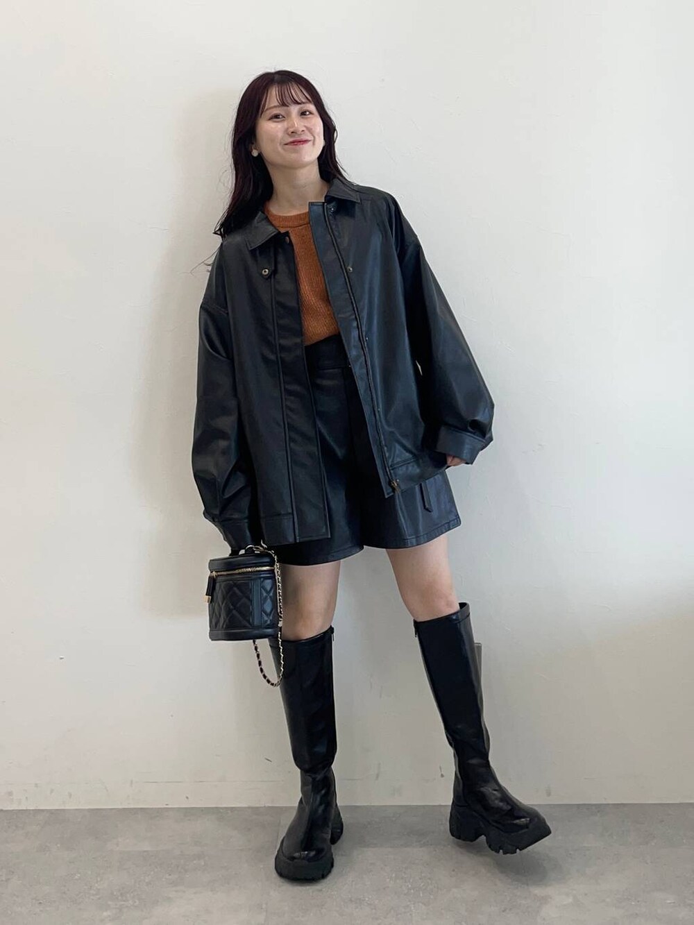 ブラック系のブーツ、ブラック系のその他パンツ、オレンジ系のニット/セーターを着用したレディースの秋コーディネートの2枚目の写真