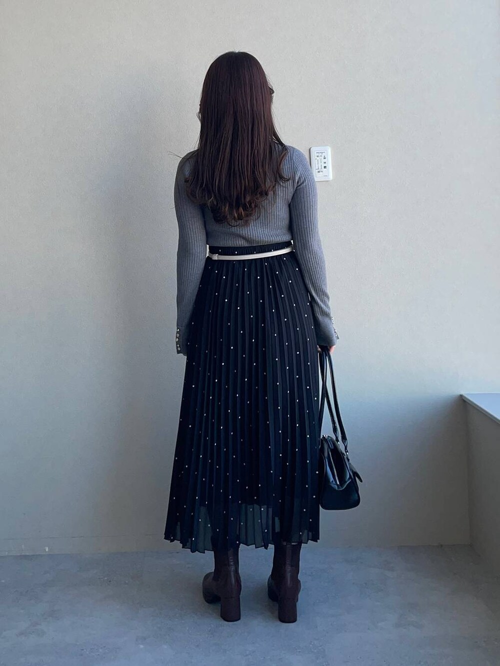 ブラウン系のブーツ、グレー系のニット/セーター、ブラック系のハンドバッグを着用したレディースの冬コーディネートの2枚目の写真