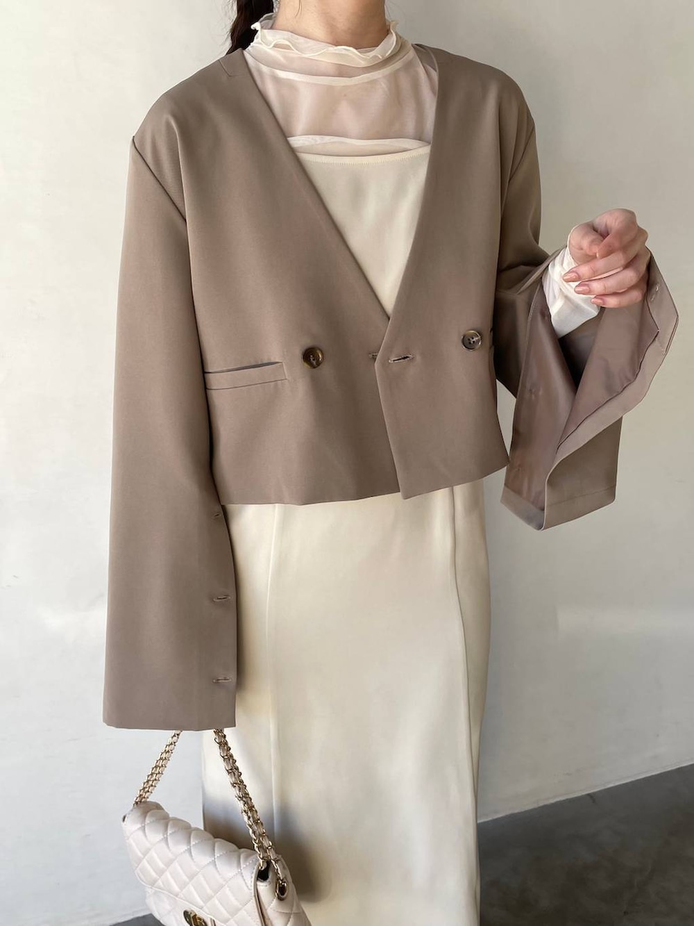 ホワイト系のドレス、ホワイト系のショルダーバッグ、ベージュ系のパンプスを着用したレディースの冬コーディネートの3枚目の写真