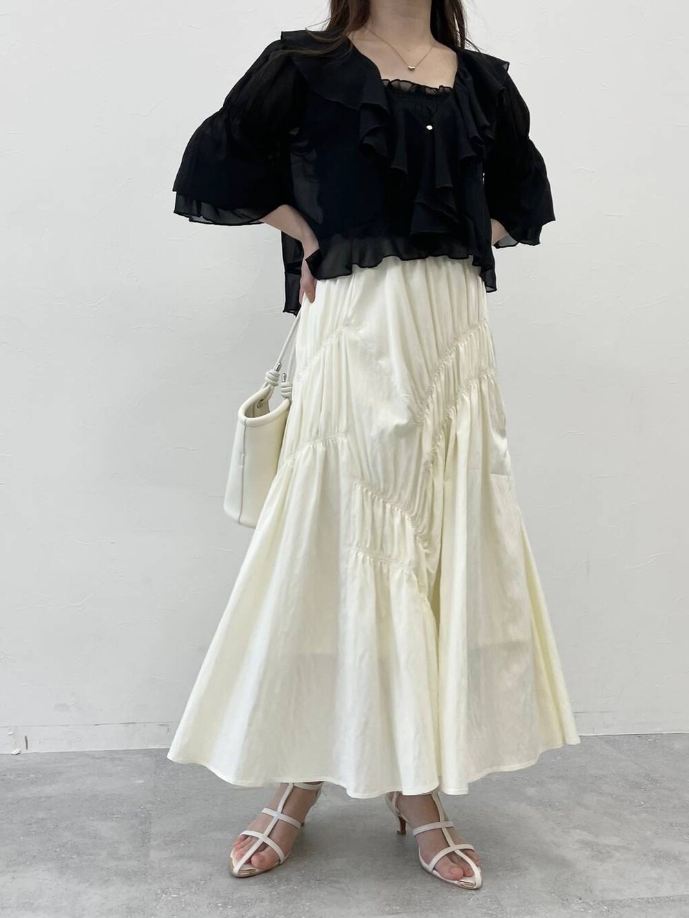 ブラック系のシャツ/ブラウス、ブラック系のハンドバッグ、ホワイト系のサンダルを着用したレディースの春コーディネートの4枚目の写真