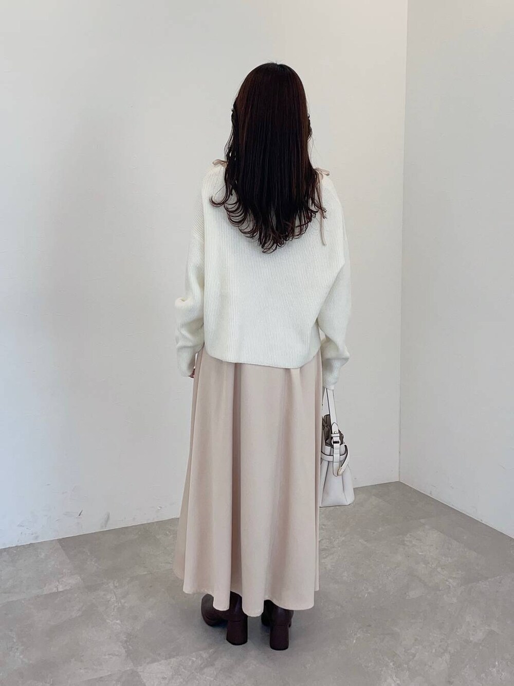 ホワイト系のショルダーバッグ、ブラウン系のブーツ、ベージュ系のワンピースを着用したレディースの冬コーディネートの2枚目の写真