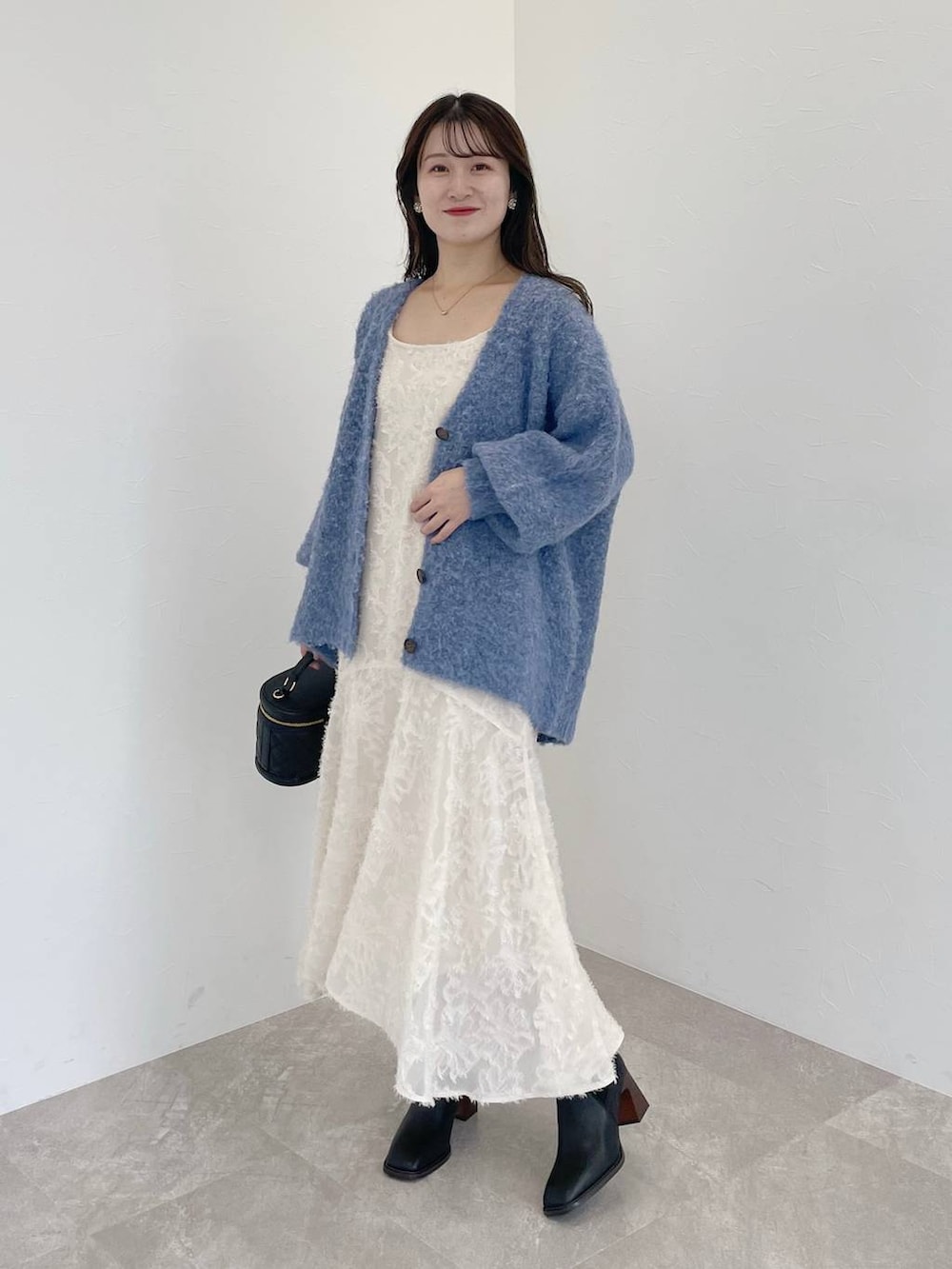 ブルー系のカーディガン/ボレロ、ブラック系のショルダーバッグ、ホワイト系のワンピースを着用したレディースの秋コーディネートの2枚目の写真