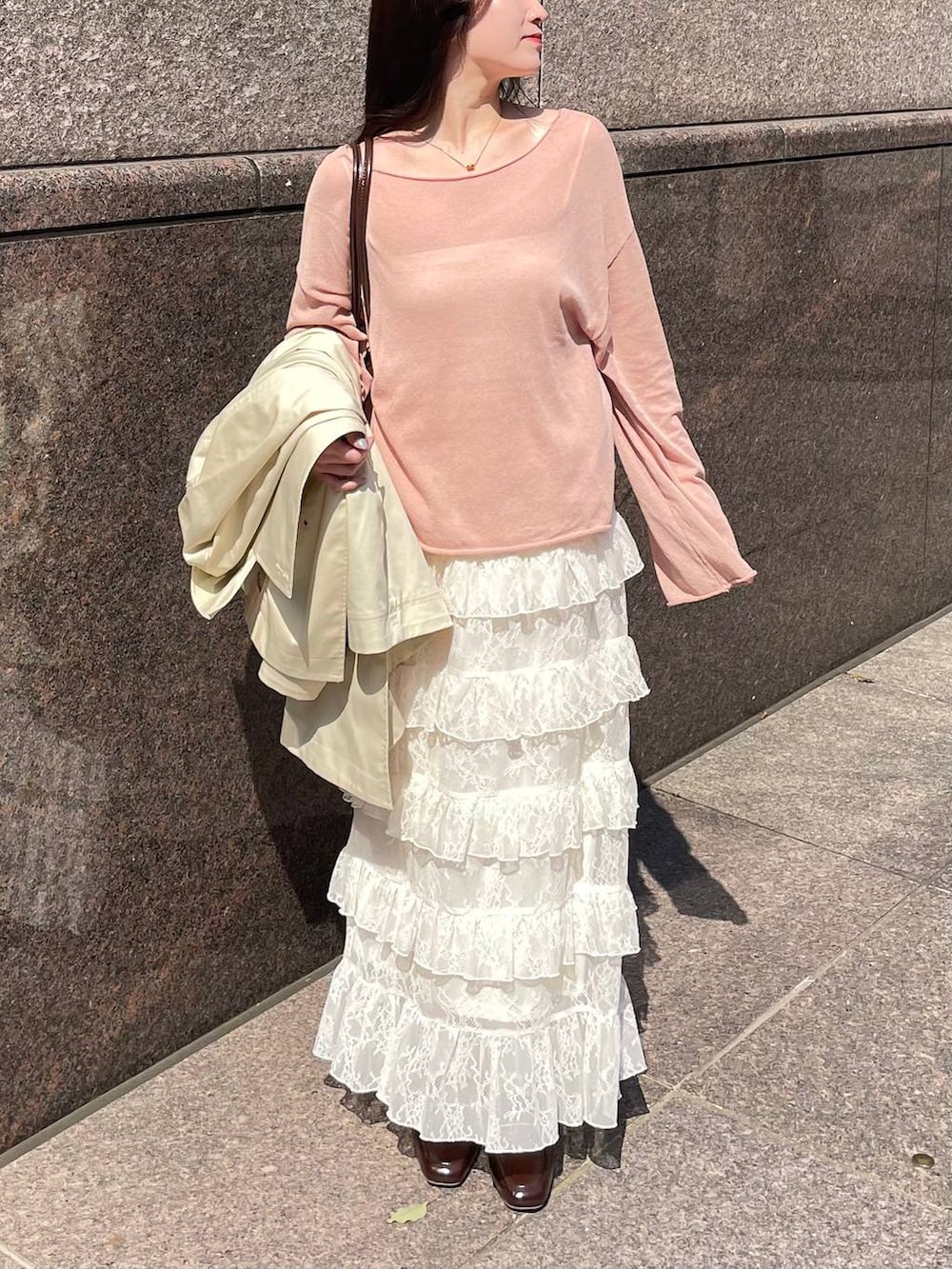 ピンク系のニット/セーター、ブラウン系のハンドバッグ、ベージュ系のトレンチコートを着用したレディースの春コーディネートの4枚目の写真