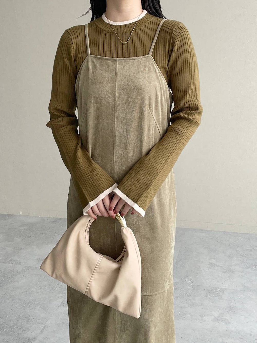 ベージュ系のハンドバッグ、ベージュ系のワンピース、ブラウン系のブーツを着用したレディースの秋コーディネートの3枚目の写真