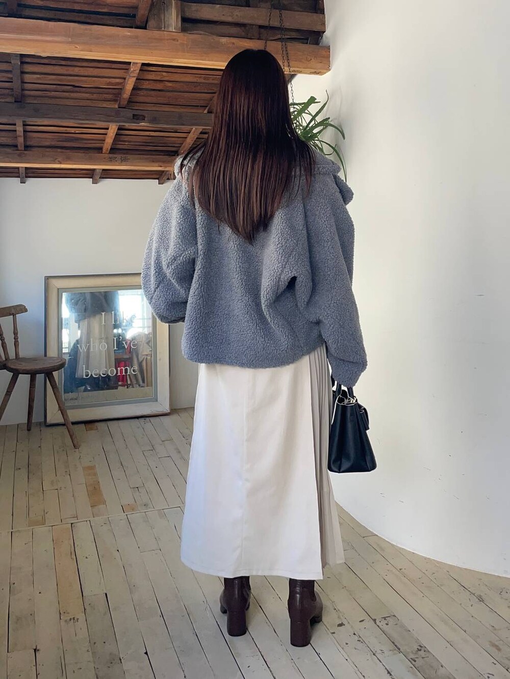 グレー系のピーコート、ブラウン系のブーツ、ホワイト系のスカートを着用したレディースの冬コーディネートの2枚目の写真