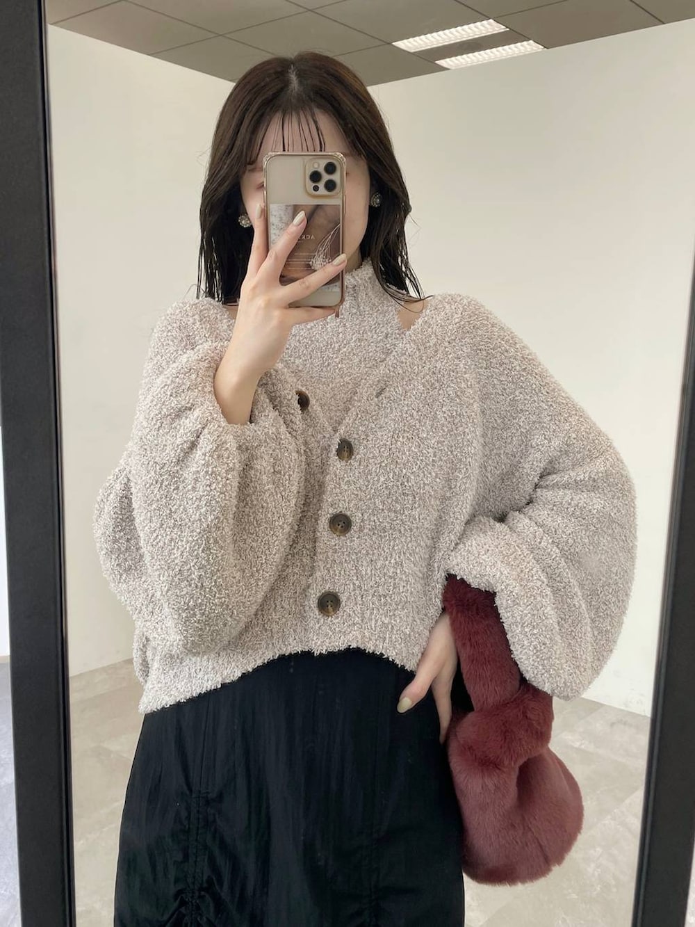 ブラック系のブーツ、ピンク系のハンドバッグ、ブラック系のスカートを着用したレディースの秋コーディネートの4枚目の写真