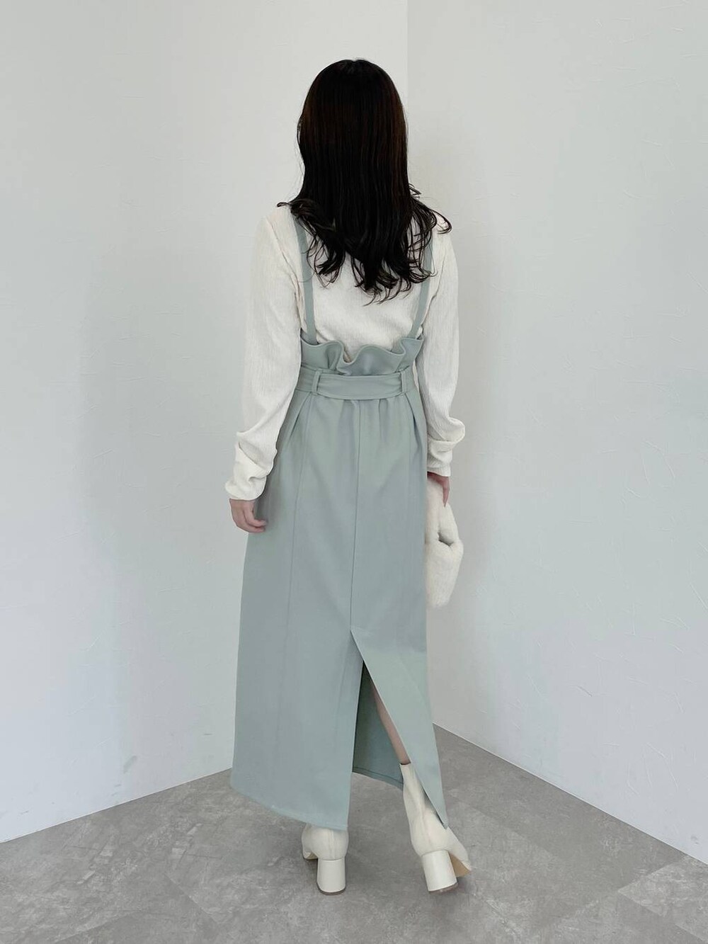 ホワイト系のブーツ、ホワイト系のハンドバッグ、ホワイト系のチェスターコートを着用したレディースの冬コーディネートの5枚目の写真