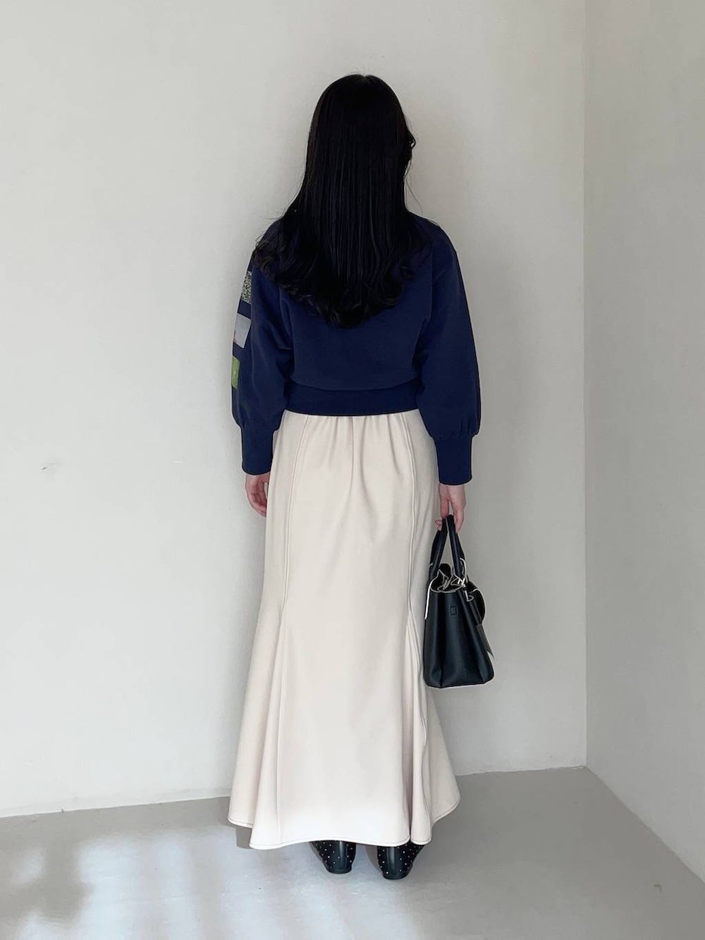 ブラック系のショルダーバッグ、ブラック系のバレエシューズ、ホワイト系のスカートを着用したレディースの春コーディネートの2枚目の写真