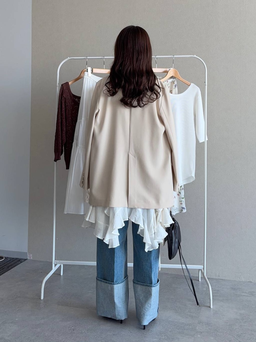 ブラック系のサンダル、ベージュ系のテーラードジャケット、ブルー系のデニムパンツを着用したレディースの春コーディネートの2枚目の写真