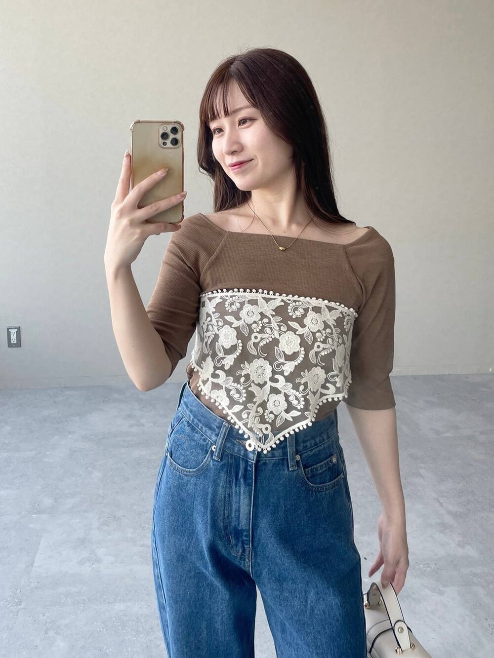 ホワイト系のショルダーバッグ、ブラウン系のTシャツ/カットソー、ブルー系のデニムパンツを着用したレディースの秋コーディネートの3枚目の写真