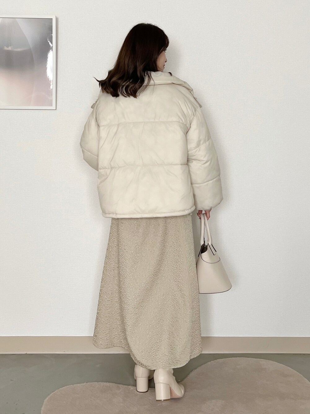 レッド系のニット/セーター、ホワイト系のブルゾン、ホワイト系のスカートを着用したレディースの冬コーディネートの2枚目の写真