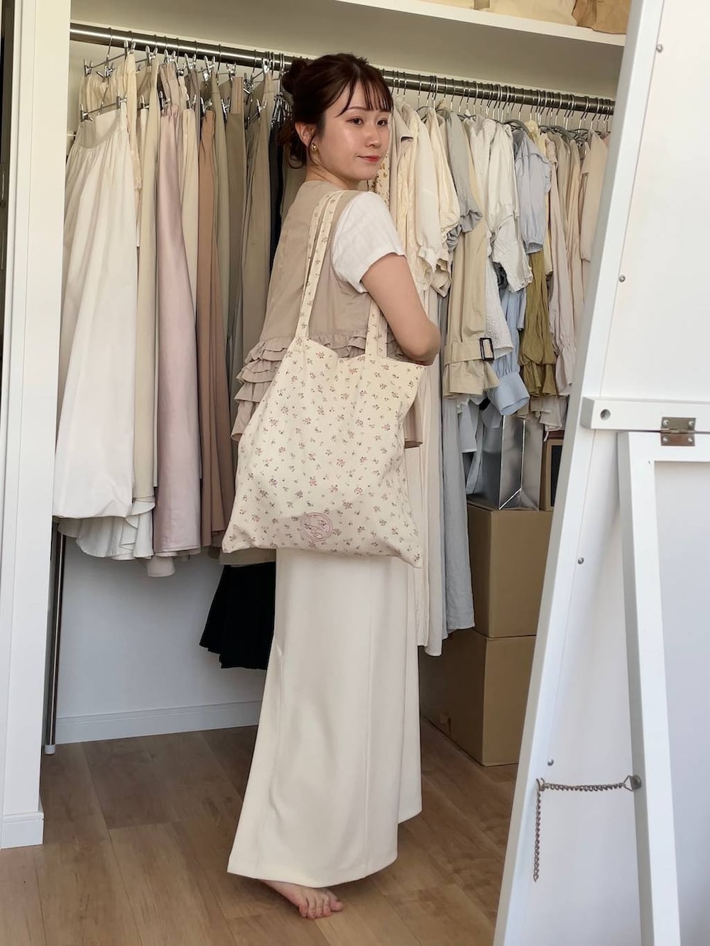 その他のトートバッグ、ベージュ系のベスト、ホワイト系のスカートを着用したレディースの夏コーディネートの2枚目の写真