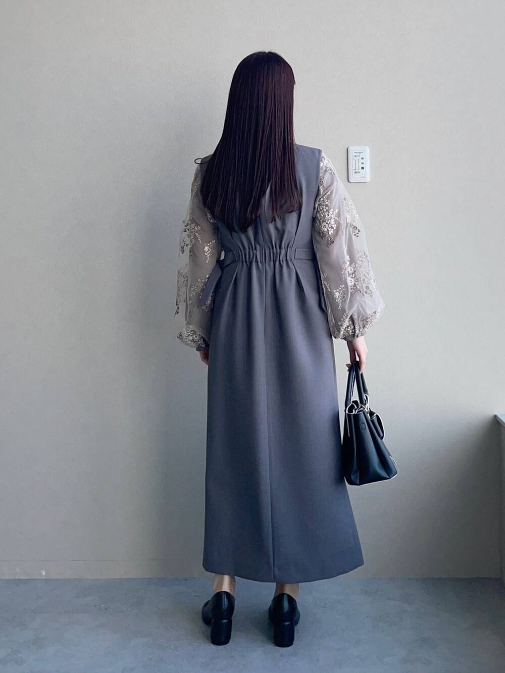 ブラウン系のシャツ/ブラウス、ブラック系のショルダーバッグ、グレー系のジャンパースカートを着用したレディースの冬コーディネートの2枚目の写真