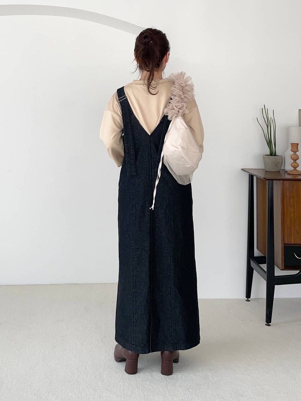 ブラック系のジャンパースカート、ベージュ系のショルダーバッグ、ブラウン系のブーツを着用したレディースの秋コーディネートの2枚目の写真