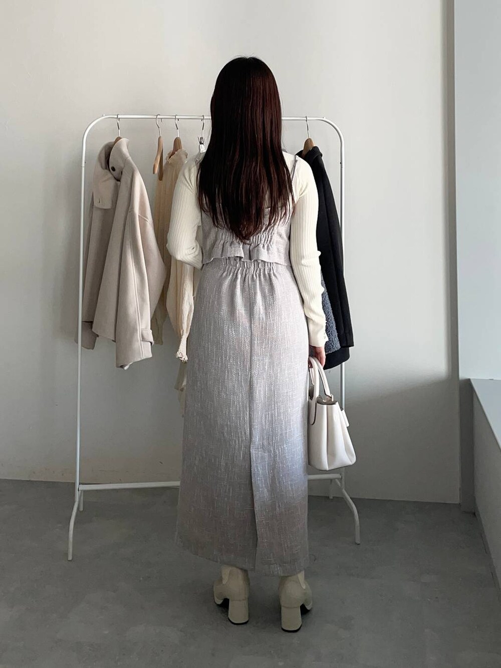 グレー系のピーコート、ホワイト系のブーツ、ホワイト系のニット/セーターを着用したレディースの冬コーディネートの4枚目の写真