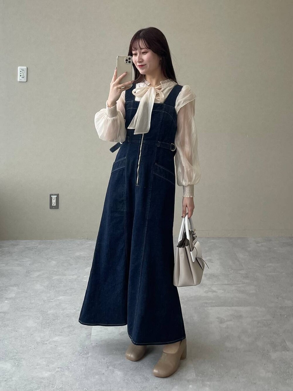 ブルー系のジャンパースカート、ベージュ系のショルダーバッグ、ブラウン系のパンプスを着用したレディースの冬コーディネートの4枚目の写真