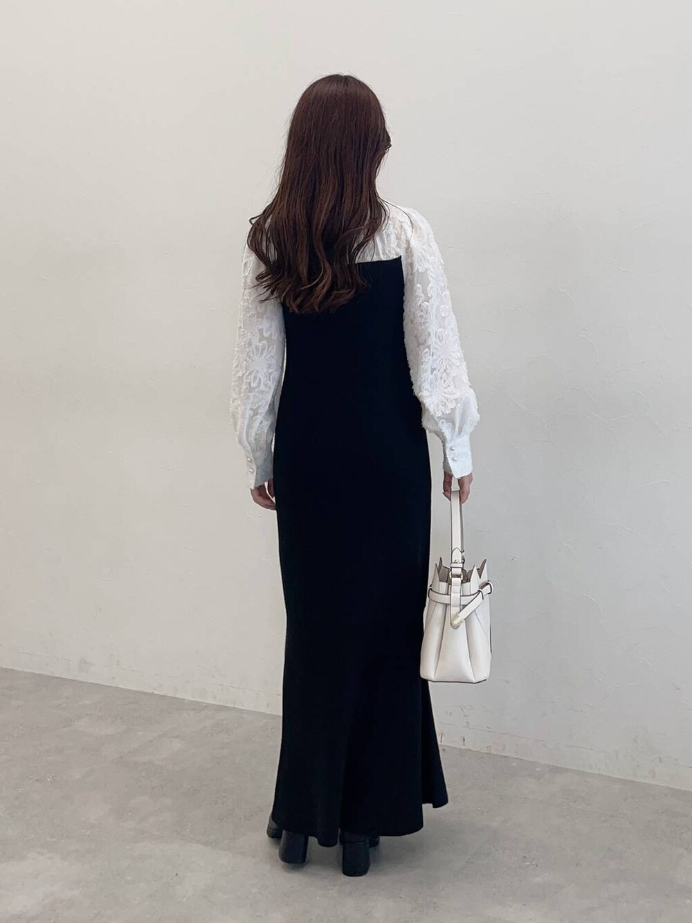 ブラック系のチェスターコート、ブラック系のワンピース、ホワイト系のショルダーバッグを着用したレディースの秋コーディネートの6枚目の写真