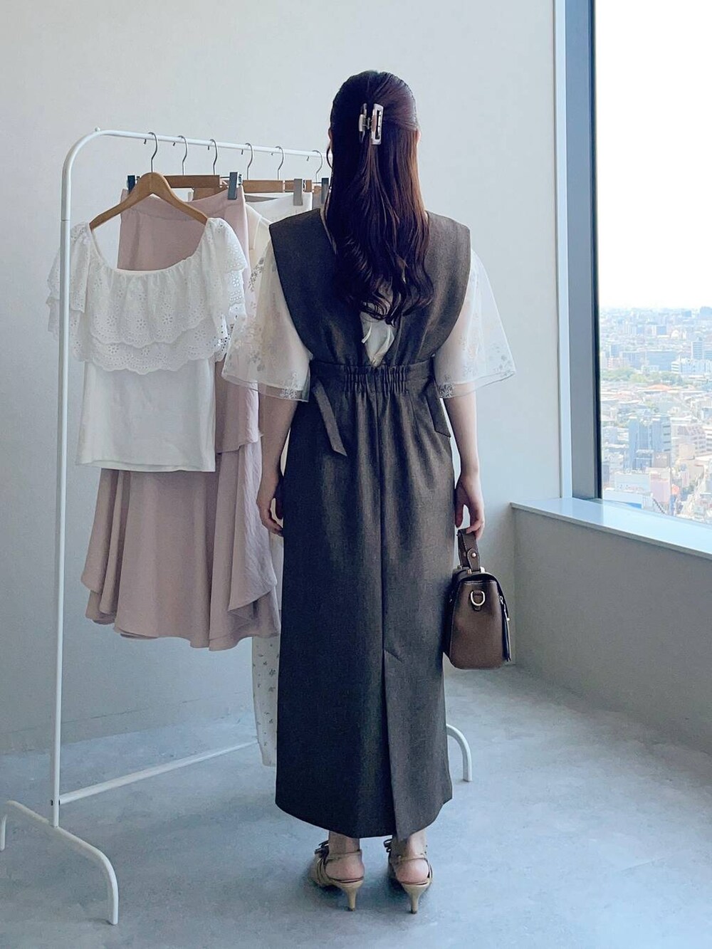 ホワイト系のシャツ/ブラウス、ゴールド系のパンプス、ブラウン系のショルダーバッグを着用したレディースの夏コーディネートの2枚目の写真