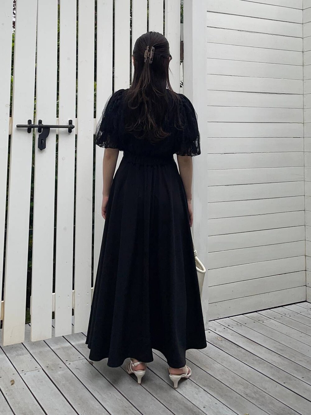 ホワイト系のハンドバッグ、ホワイト系のサンダル、ブラック系のシャツ/ブラウスを着用したレディースの夏コーディネートの2枚目の写真