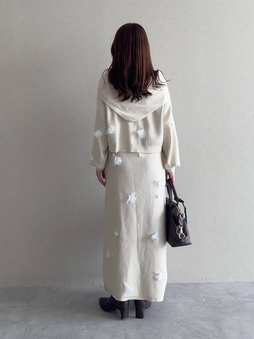 ブラウン系のボストンバッグ、ブラウン系のブーツ、ホワイト系のニット/セーターを着用したレディースの冬コーディネートの2枚目の写真