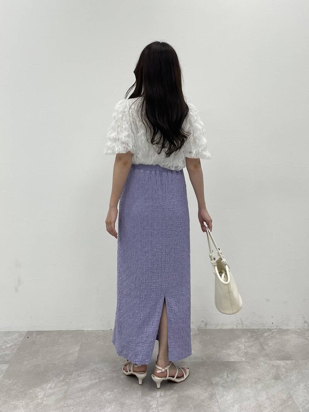 ホワイト系のハンドバッグ、パープル系のスカート、ホワイト系のサンダルを着用したレディースの夏コーディネートの2枚目の写真