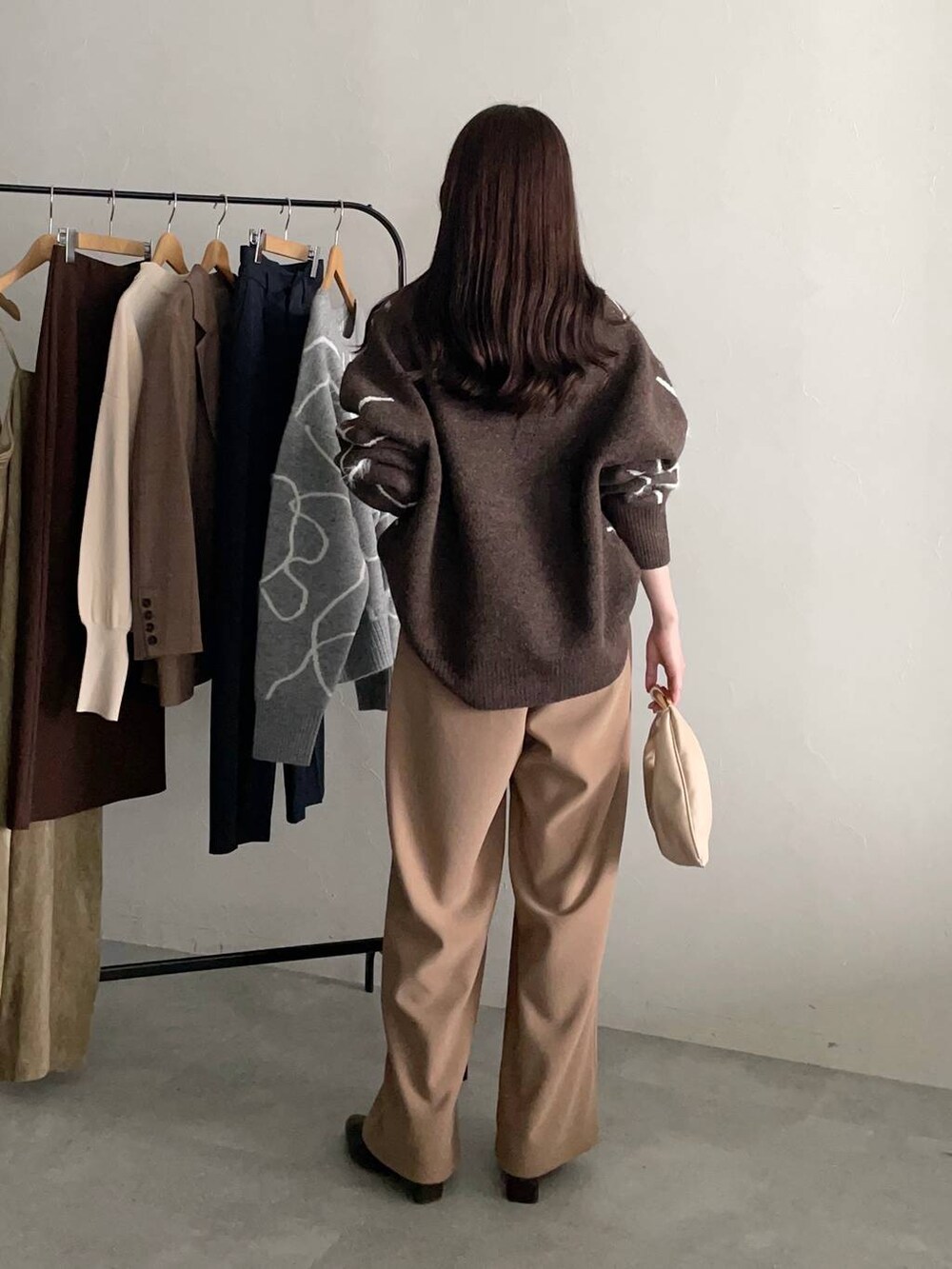 ベージュ系のハンドバッグ、ブラウン系のニット/セーター、ブラウン系のブーツを着用したレディースの秋コーディネートの2枚目の写真