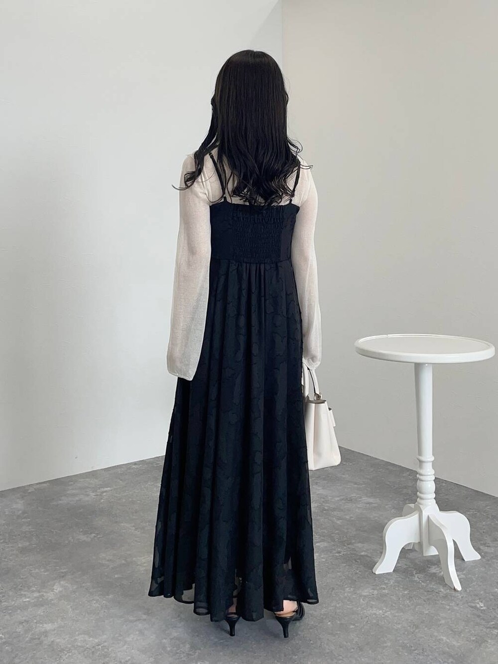 ホワイト系のショルダーバッグ、ブラック系のワンピース、ブラック系のパンプスを着用したレディースの秋コーディネートの2枚目の写真