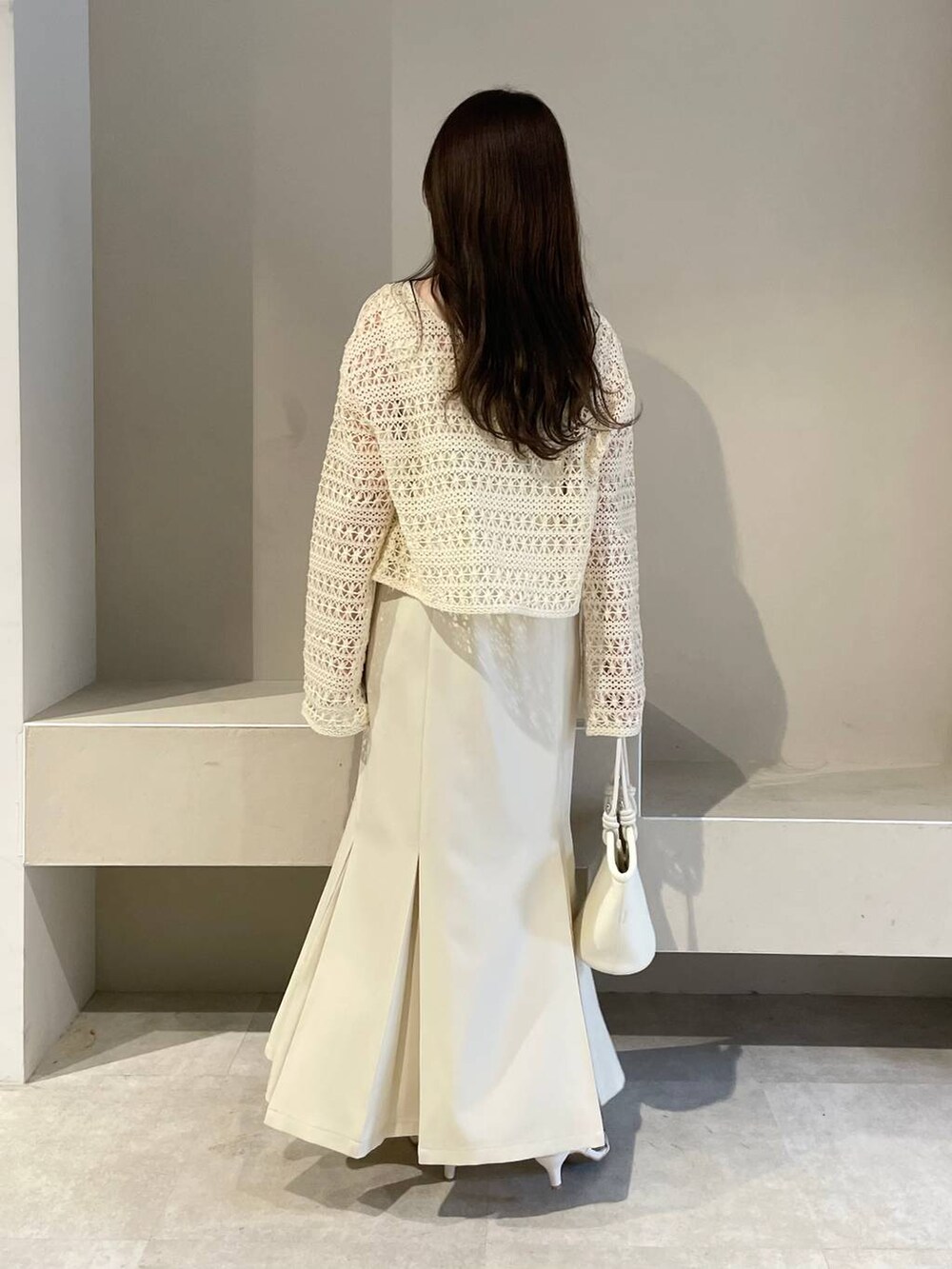 ホワイト系のハンドバッグ、ホワイト系のカーディガン/ボレロ、ホワイト系のサンダルを着用したレディースの春コーディネートの2枚目の写真