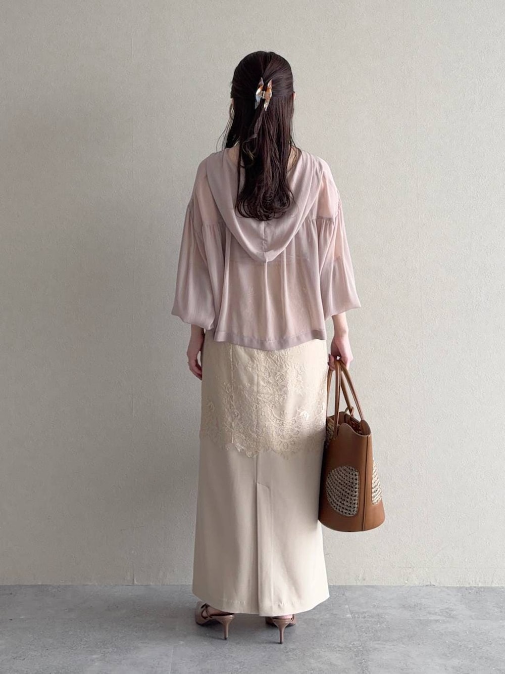 ベージュ系のパーカー、ブラウン系のトートバッグ、ベージュ系のスカートを着用したレディースの春コーディネートの2枚目の写真