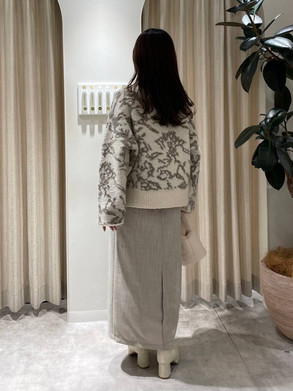 ホワイト系のブーツ、ホワイト系のハンドバッグ、ホワイト系のスカートを着用したレディースの冬コーディネートの2枚目の写真