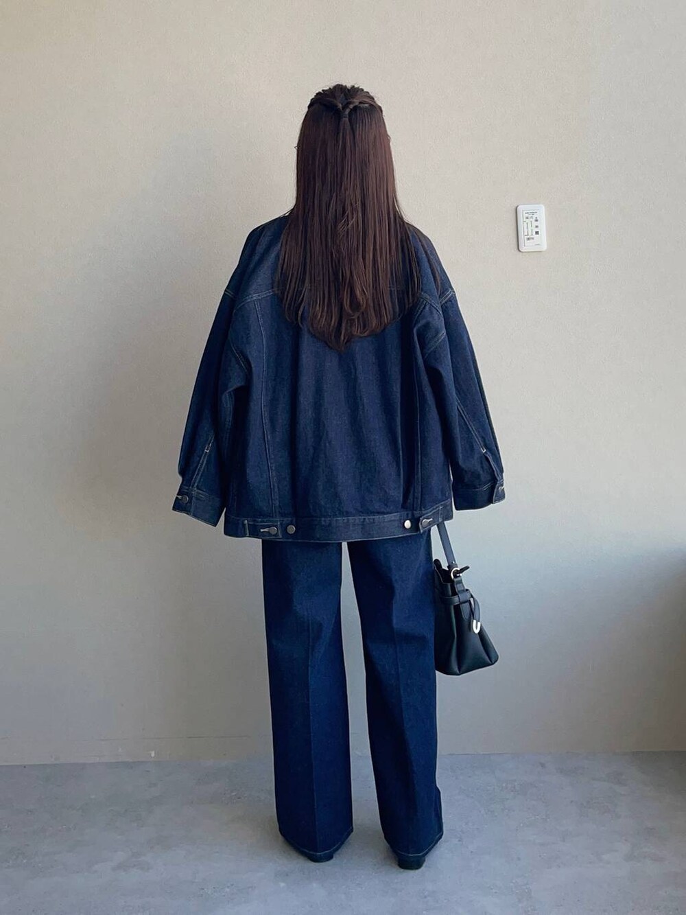 ブラック系のショルダーバッグ、ブルー系のデニムパンツ、ベージュ系のニット/セーターを着用したレディースの冬コーディネートの2枚目の写真
