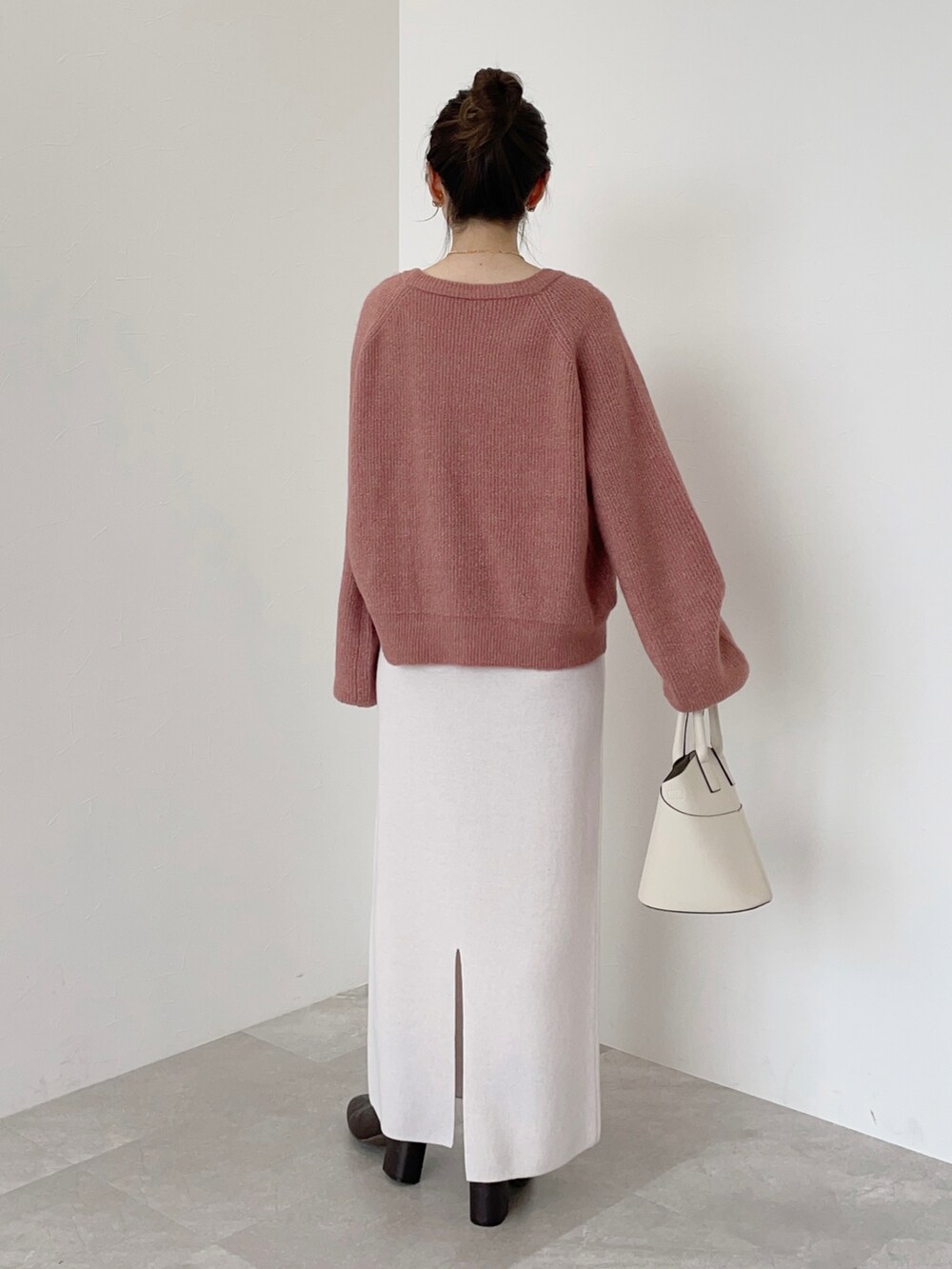 ピンク系のニット/セーター、ホワイト系のショルダーバッグ、ブラウン系のブーツを着用したレディースの冬コーディネートの2枚目の写真