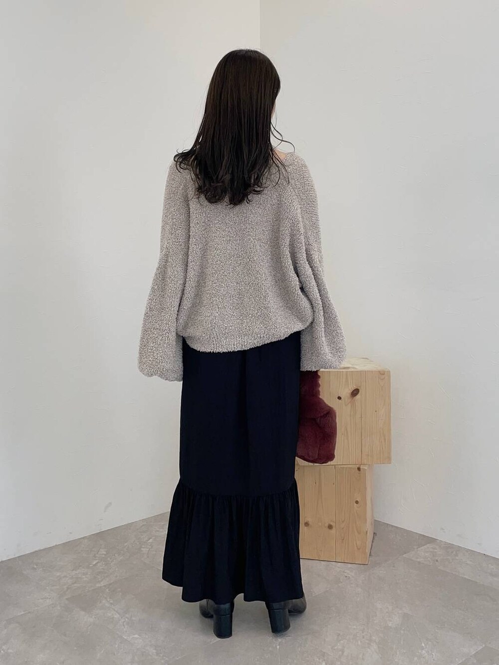 ブラック系のブーツ、ピンク系のハンドバッグ、ブラック系のスカートを着用したレディースの秋コーディネートの3枚目の写真