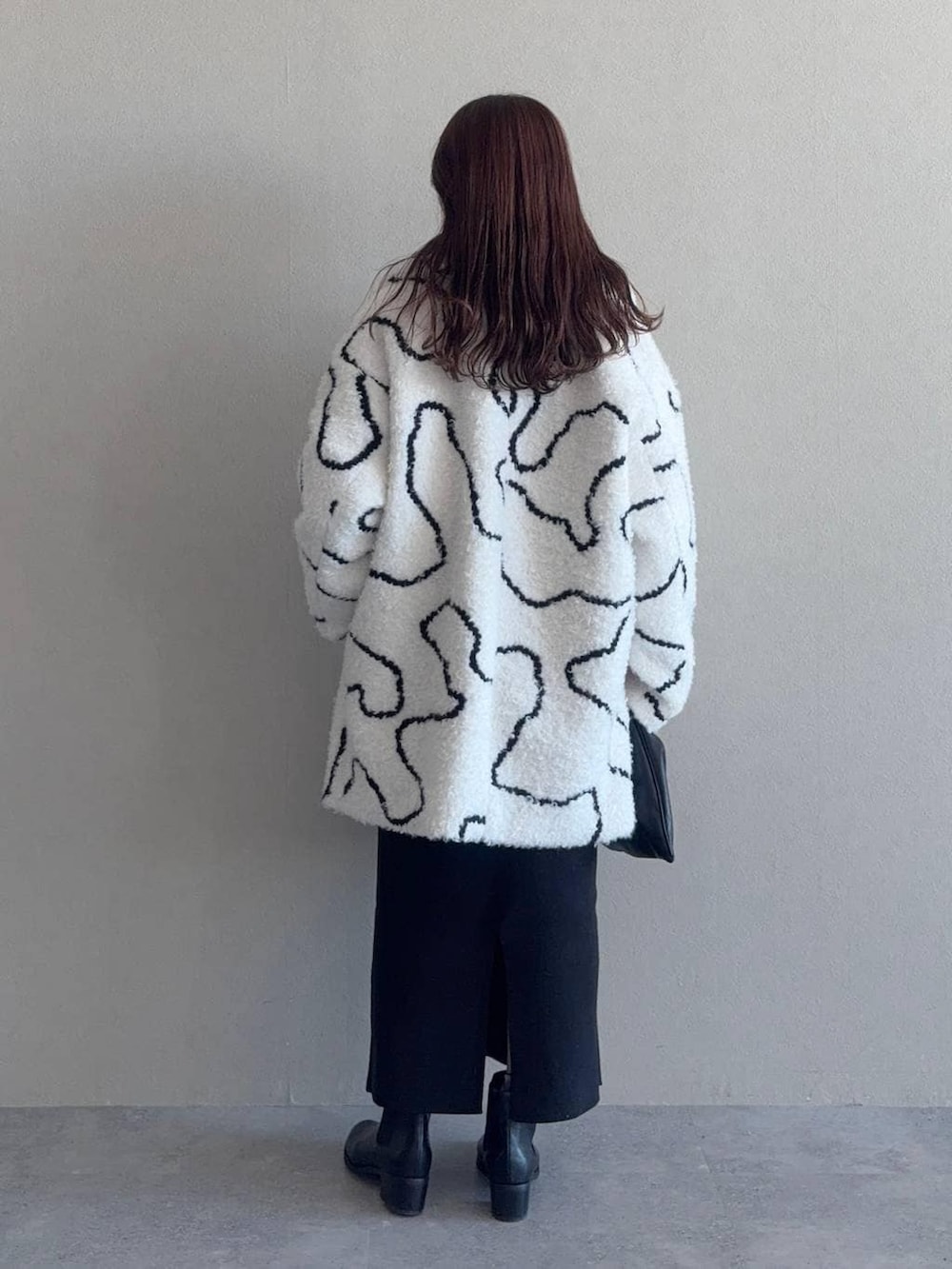 ブラック系のスカート、ブラック系のハンドバッグ、ホワイト系のステンカラーコートを着用したレディースの冬コーディネートの2枚目の写真