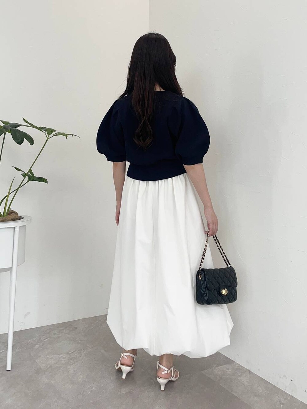 ホワイト系のスカート、ブラック系のショルダーバッグ、ホワイト系のサンダルを着用したレディースの夏コーディネートの2枚目の写真