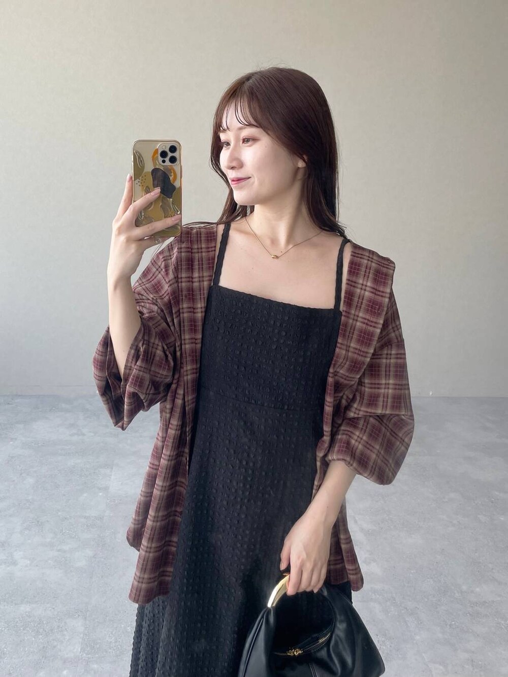 ブラック系のハンドバッグ、ブラック系のワンピース、レッド系のシャツ/ブラウスを着用したレディースの夏コーディネートの3枚目の写真