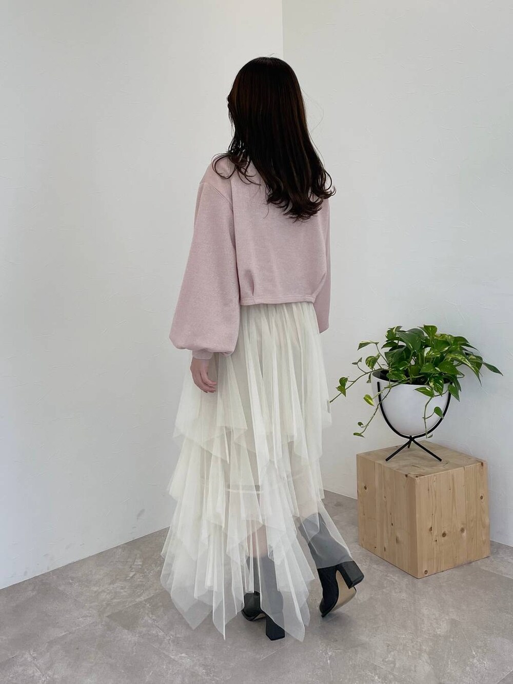 グレー系のブーツ、ブラック系のショルダーバッグ、ホワイト系のスカートを着用したレディースの冬コーディネートの2枚目の写真