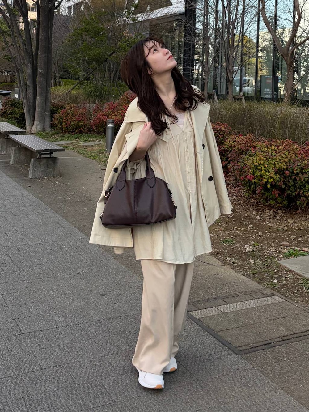 ブラウン系のボストンバッグ、ホワイト系のシャツ/ブラウス、ベージュ系のスラックスを着用したレディースの春コーディネートの2枚目の写真