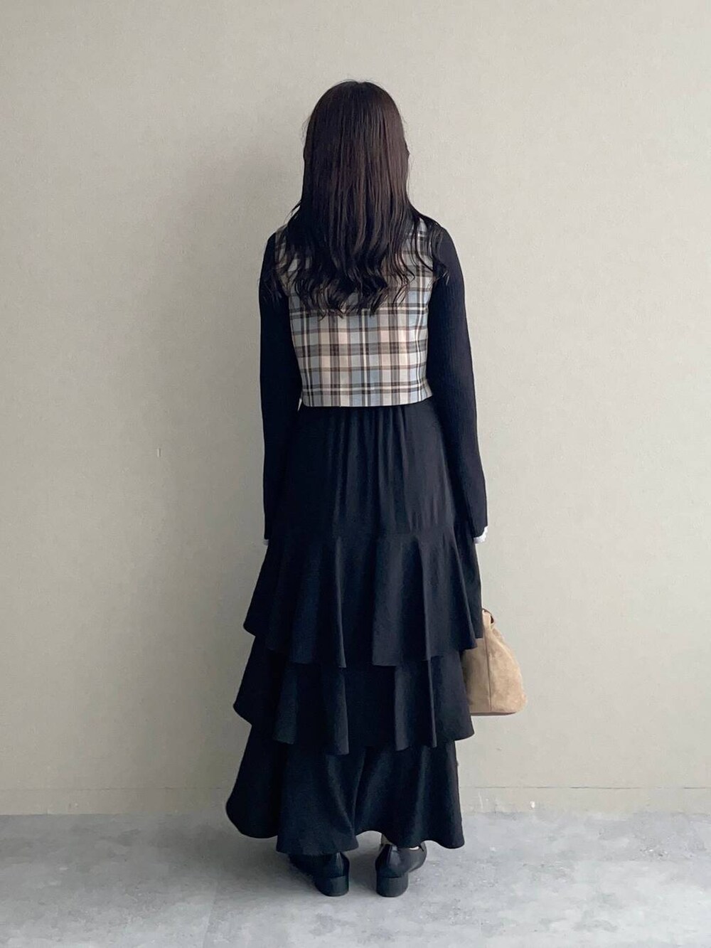 ブラック系のスカート、ブラック系のローファー、ベージュ系のハンドバッグを着用したレディースの秋コーディネートの2枚目の写真