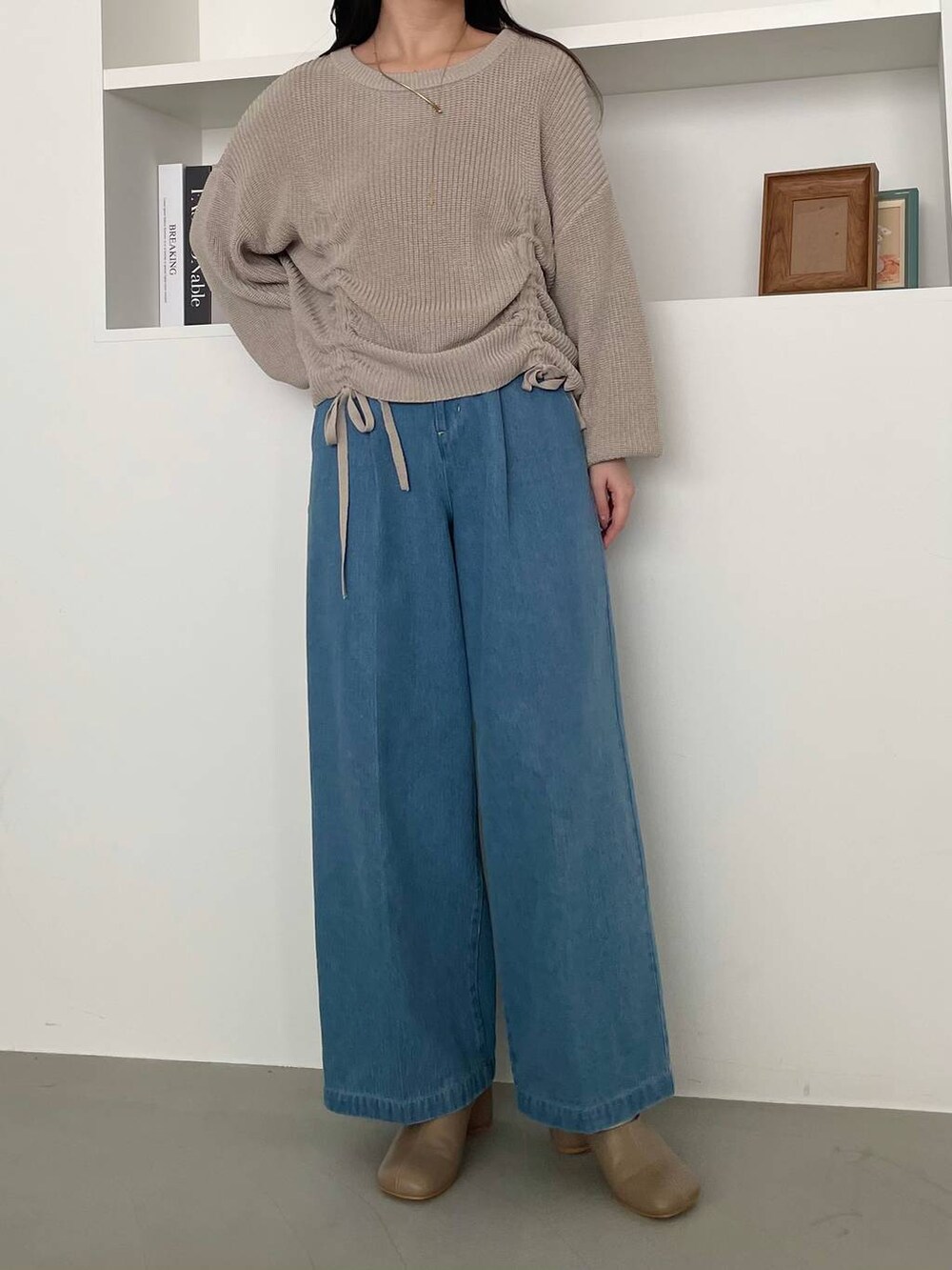ベージュ系のショルダーバッグ、ブラウン系のパンプス、ブルー系のデニムパンツを着用したレディースの冬コーディネートの4枚目の写真