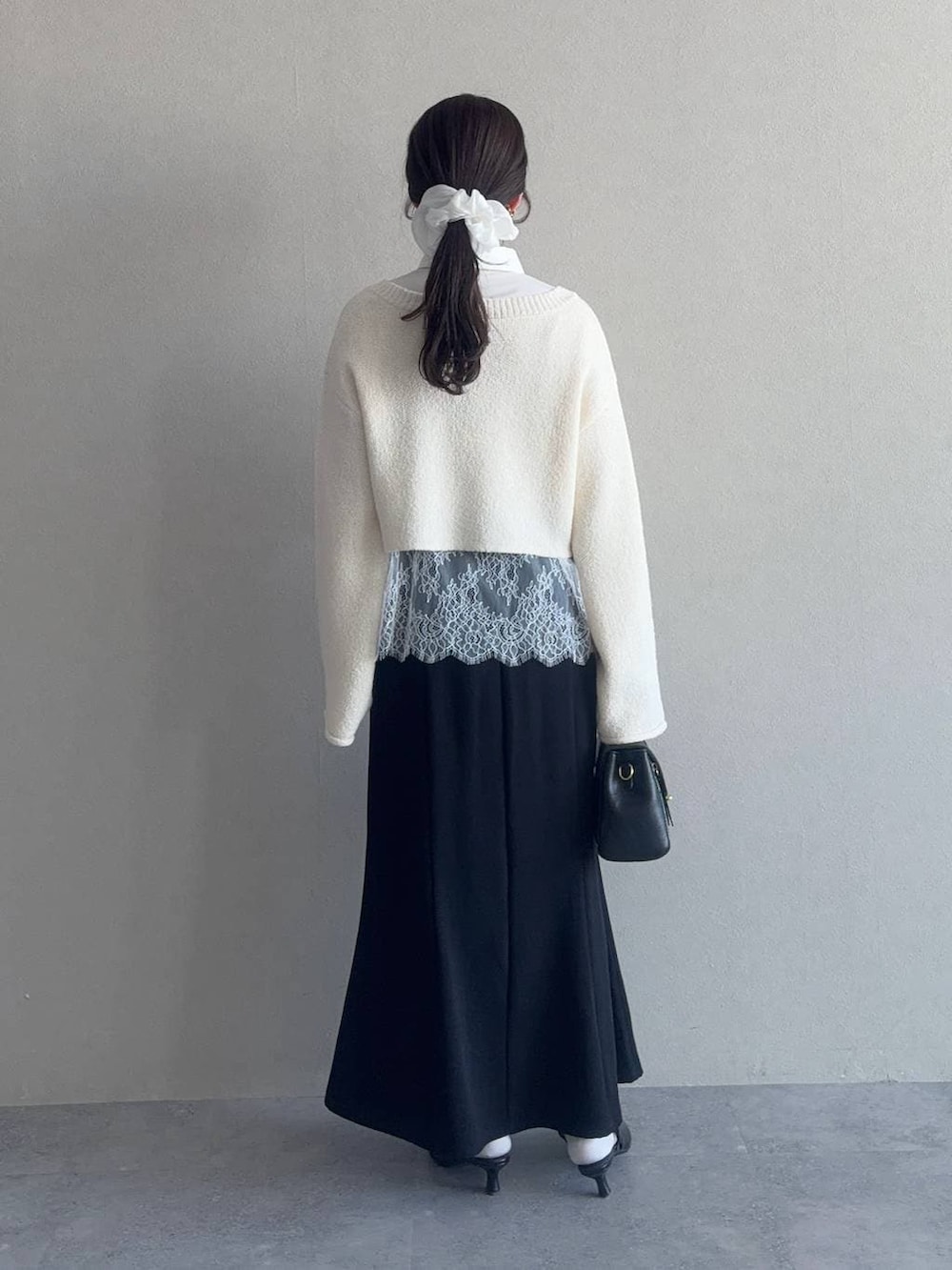 ブラック系のショルダーバッグ、ホワイト系のサンダル、ホワイト系のニット/セーターを着用したレディースの冬コーディネートの2枚目の写真