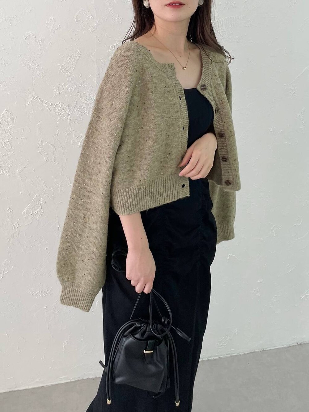 ブラック系のショルダーバッグ、ブラック系のジャンパースカート、ブラック系のパンプスを着用したレディースの秋コーディネートの3枚目の写真