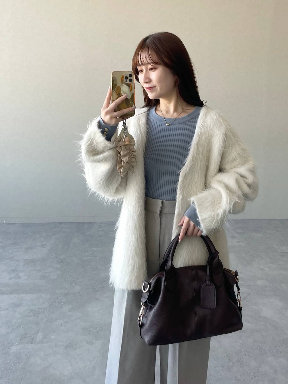 ブラウン系のボストンバッグ、ブラウン系のブーツ、ブルー系のニット/セーターを着用したレディースの冬コーディネートの3枚目の写真