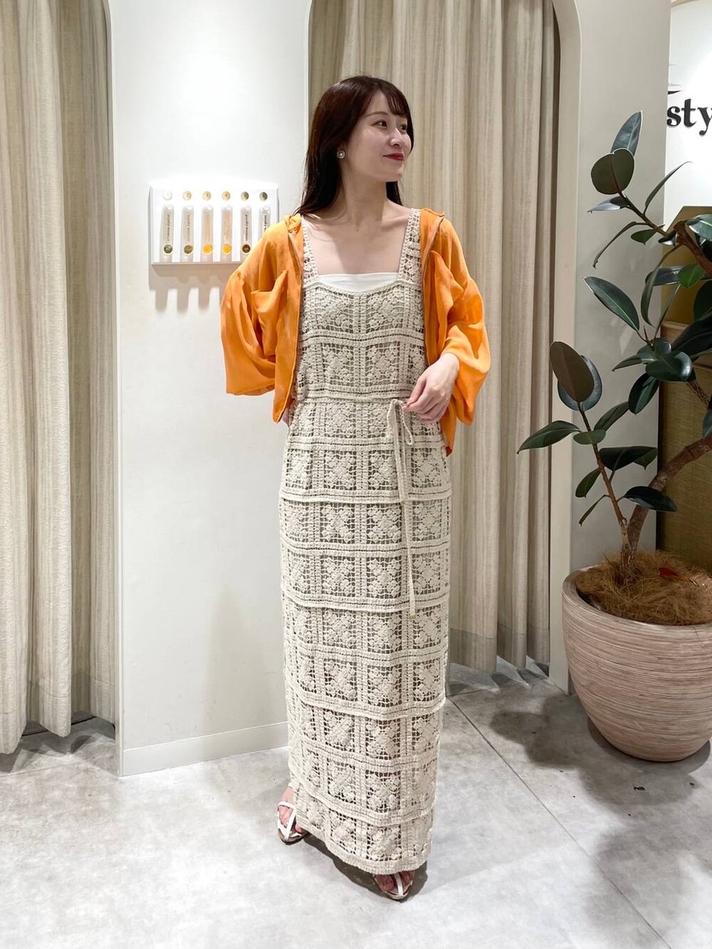 ホワイト系のワンピース、オレンジ系のパーカー、ホワイト系のサンダルを着用したレディースの夏コーディネートの2枚目の写真