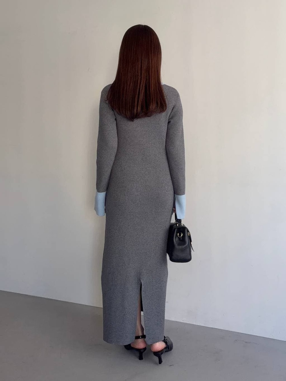 ブラック系のショルダーバッグ、グレー系のワンピース、ブラック系のサンダルを着用したレディースの冬コーディネートの2枚目の写真