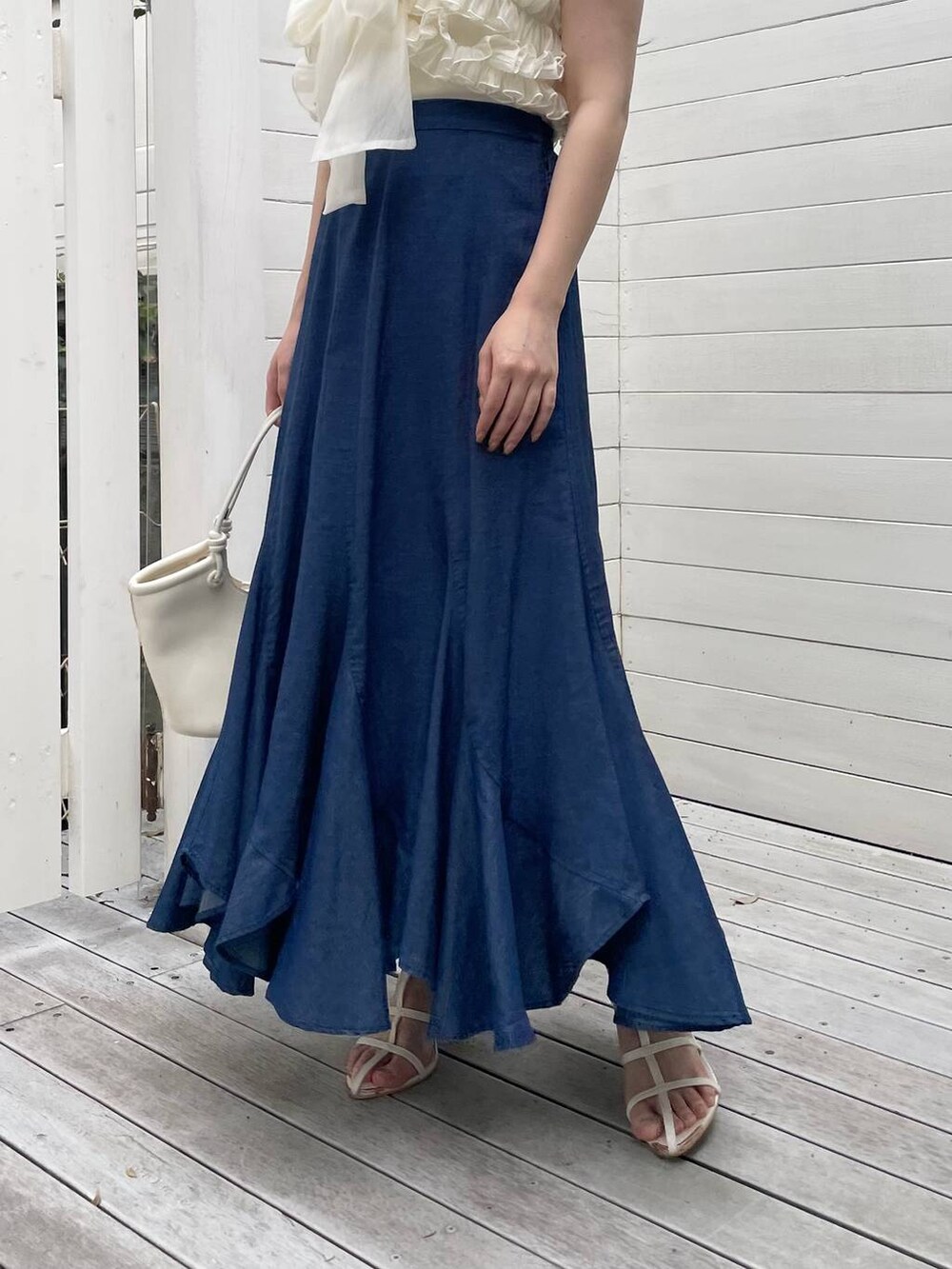 ホワイト系のハンドバッグ、ブルー系のスカート、ホワイト系のサンダルを着用したレディースの夏コーディネートの4枚目の写真