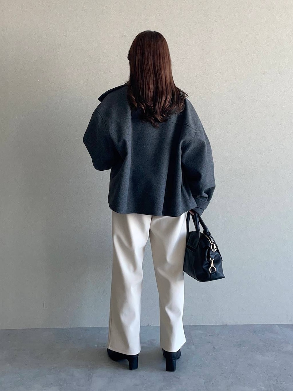 グレー系のピーコート、ブラック系のボストンバッグ、ブラック系のブーツを着用したレディースの冬コーディネートの2枚目の写真