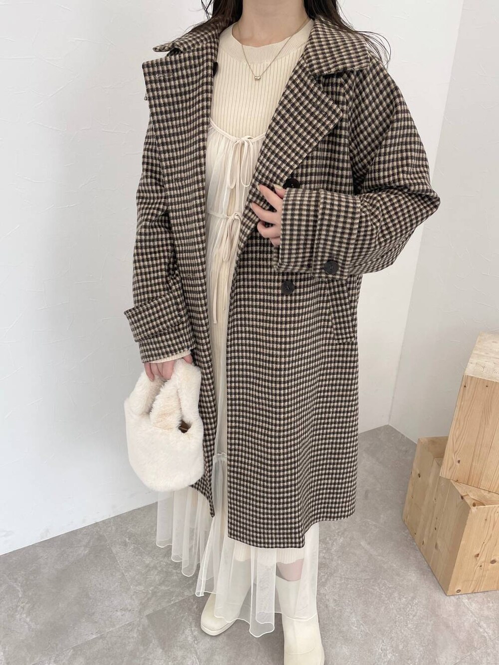 ホワイト系のブーツ、ホワイト系のハンドバッグ、ブラウン系のチェスターコートを着用したレディースの秋コーディネートの3枚目の写真