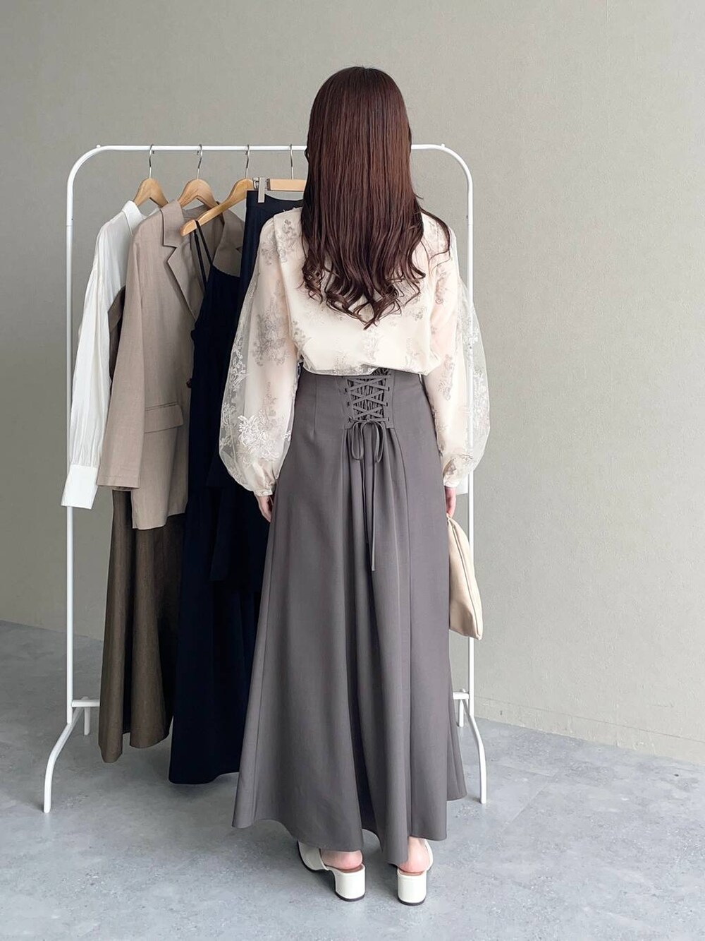 ベージュ系のハンドバッグ、ホワイト系のシャツ/ブラウス、ブラウン系のスカートを着用したレディースの秋コーディネートの2枚目の写真