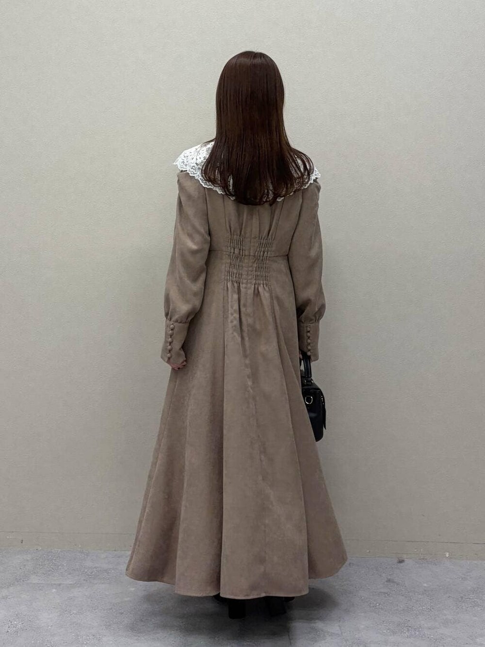 ブラック系のブーツ、ブラック系のショルダーバッグ、ベージュ系のワンピースを着用したレディースの冬コーディネートの2枚目の写真